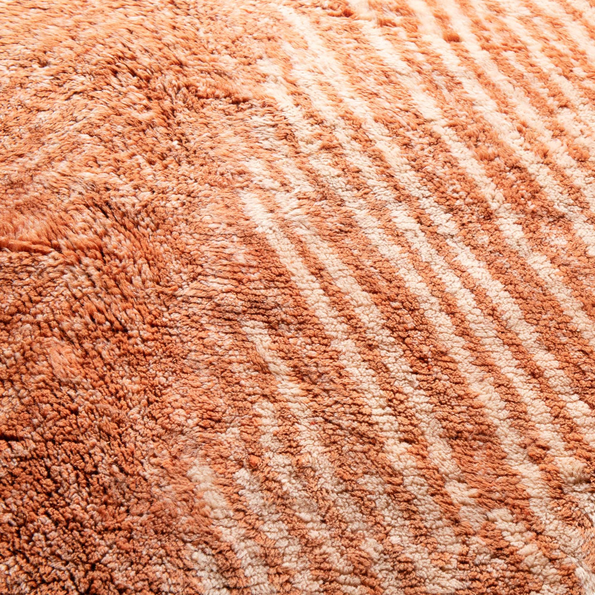 closeup Handmade Moroccan wool rug in coral orange and ivory with radiating chevron stripes