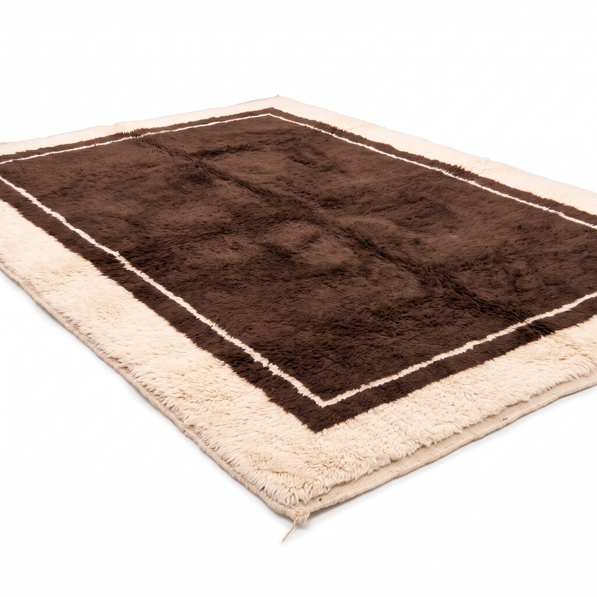 Chocolate brown hand-knotted Moroccan shag rug with cream border, angled view showing the plush wool pile