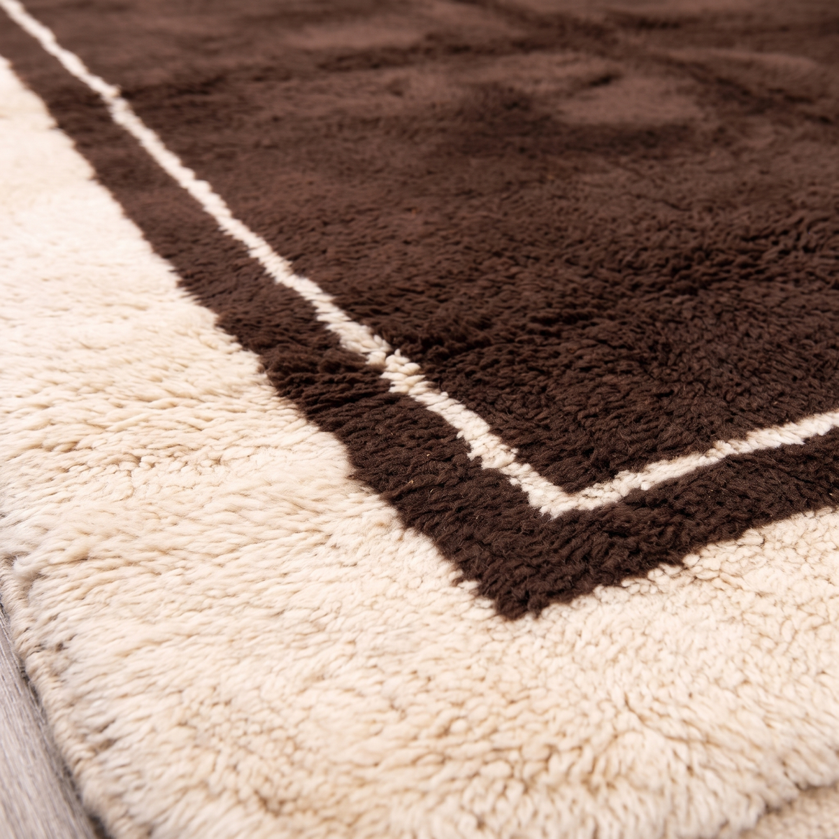 Close-up of the carved cream border and thin inner line on a chocolate brown Beni Mrirt wool rug
