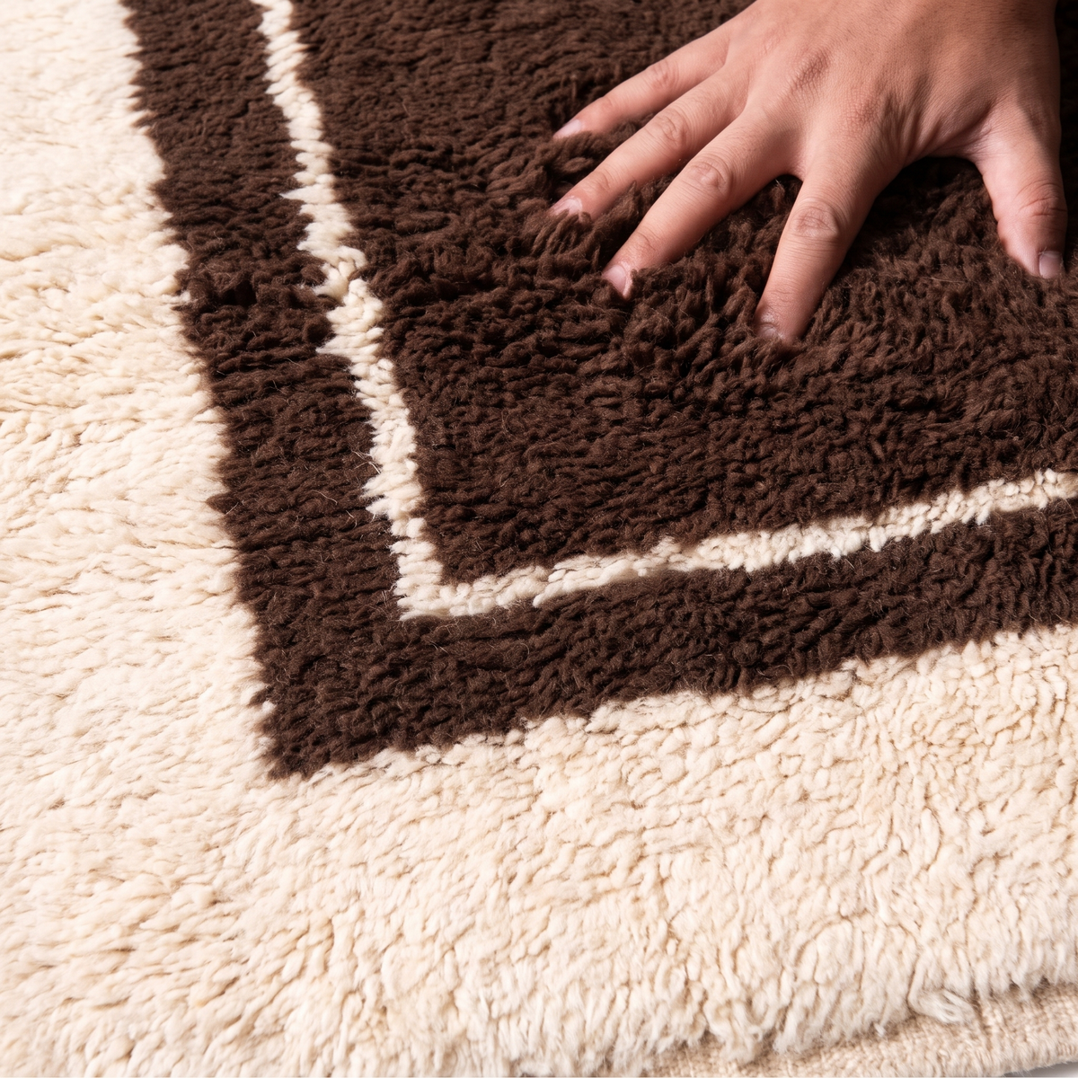 Hand pressing into the deep plush pile of a chocolate brown hand-knotted wool rug