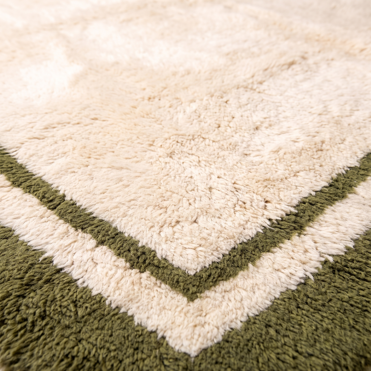 Close-up of the carved olive green border and thin inner line on a cream Beni Mrirt wool rug