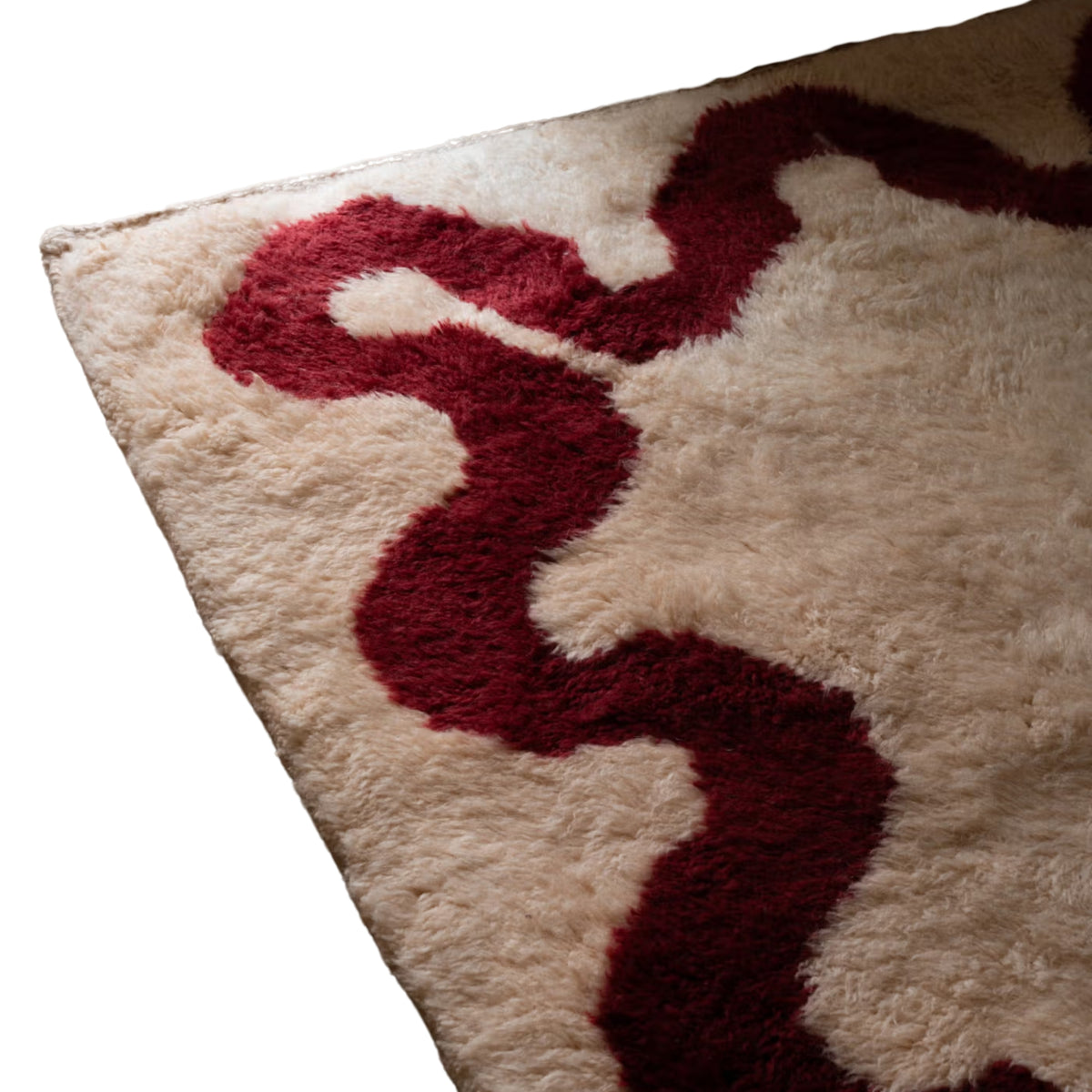 closeup Handmade Moroccan wool rug in cream with garnet-red wavy border and natural fringe