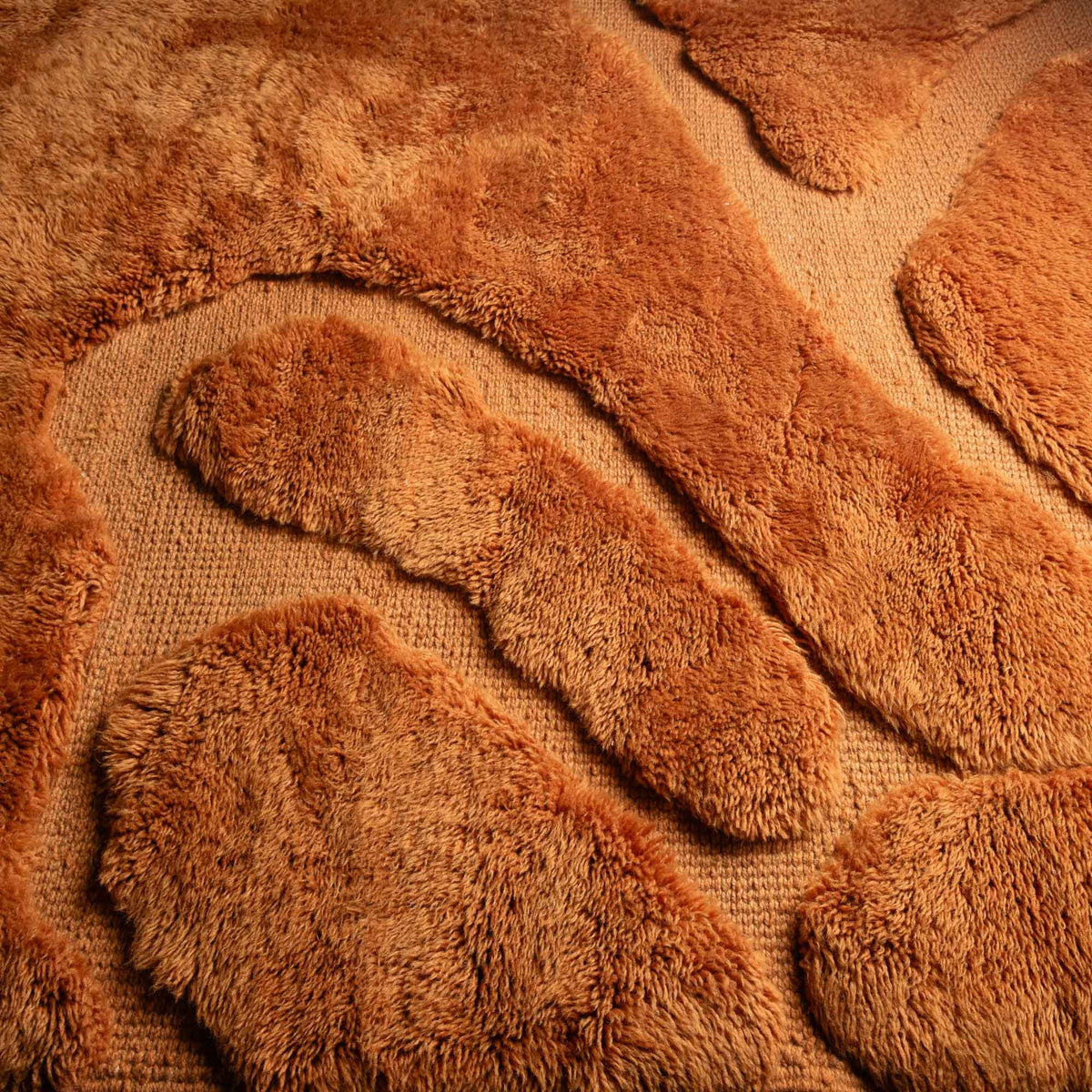 closeup Handmade Moroccan wool rug in amber orange with organic free-form shapes and fringe