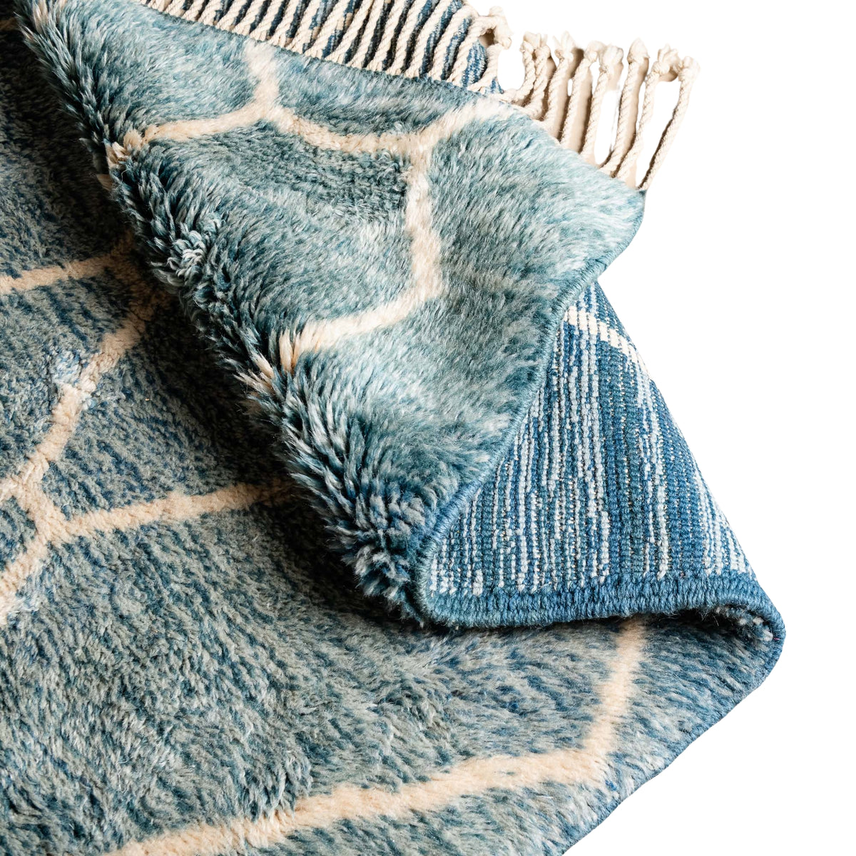 closeup flipped Handmade Moroccan wool rug in aquamarine blue with cream geometric lattice pattern and fringe
