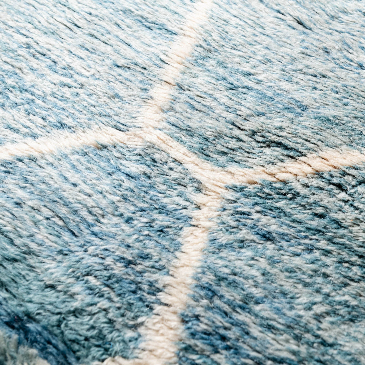Closeup Handmade Moroccan wool rug in aquamarine blue with cream geometric lattice pattern and fringe