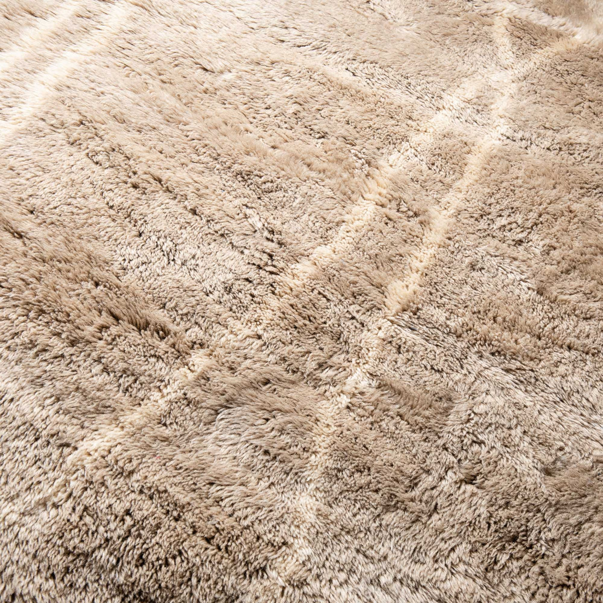 closeup Handmade Moroccan wool rug in sand beige with ivory undulating line motifs