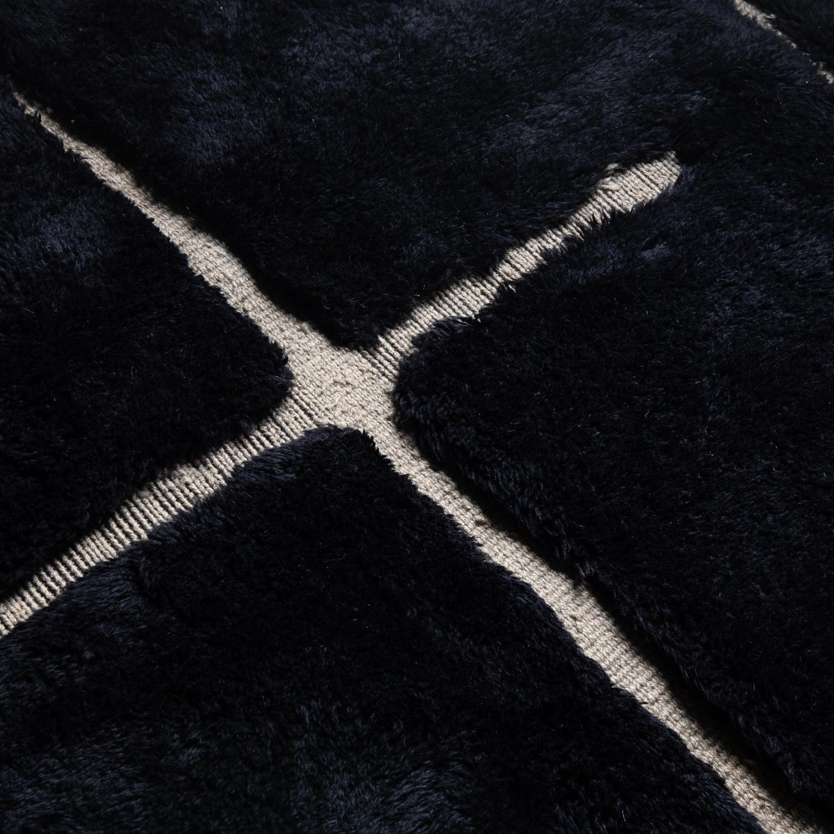 Closeup Handmade Moroccan wool rug in charcoal black with beige abstract grid lines
