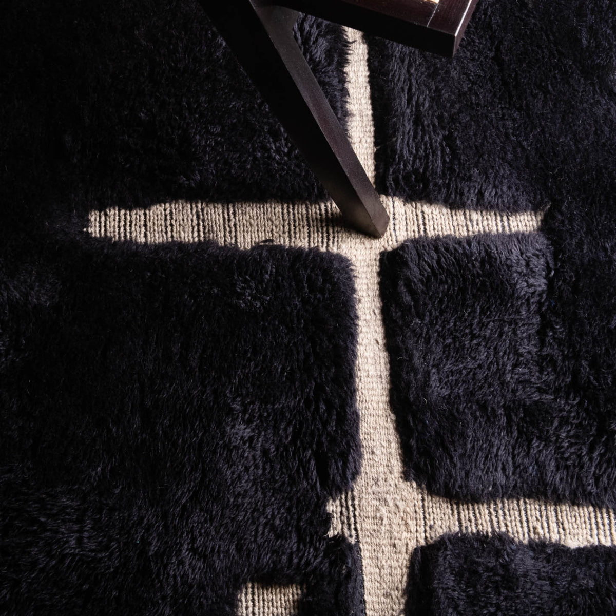 Closeup Handmade Moroccan wool rug in charcoal black with beige abstract grid lines