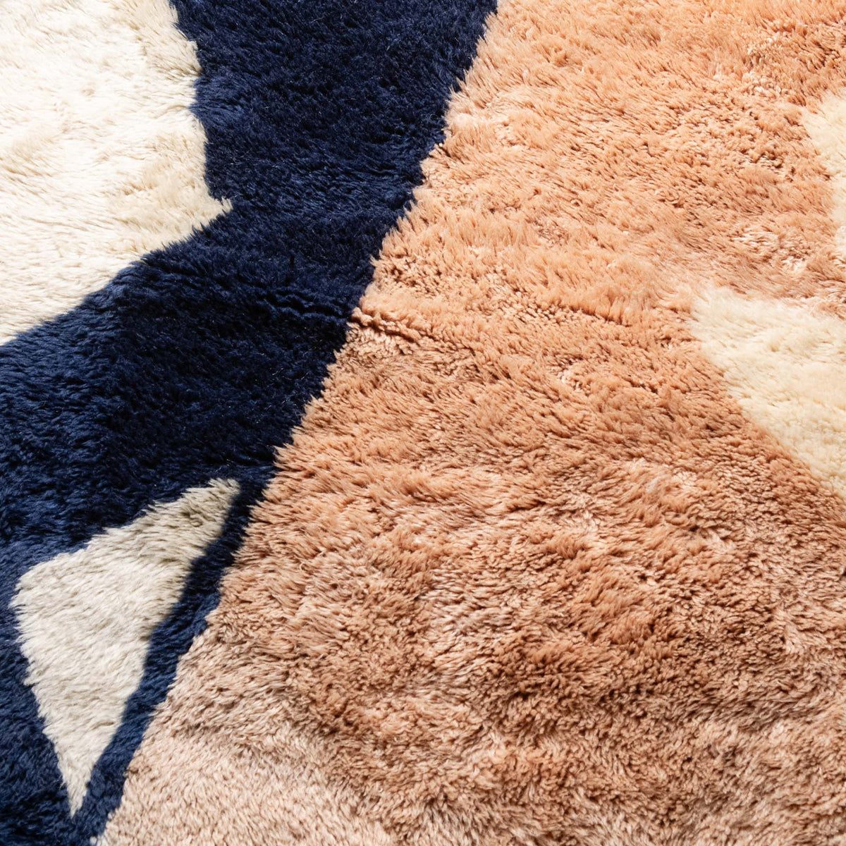 Closeup Handmade Moroccan wool rug blush sand with carved ivory islands and navy stripe