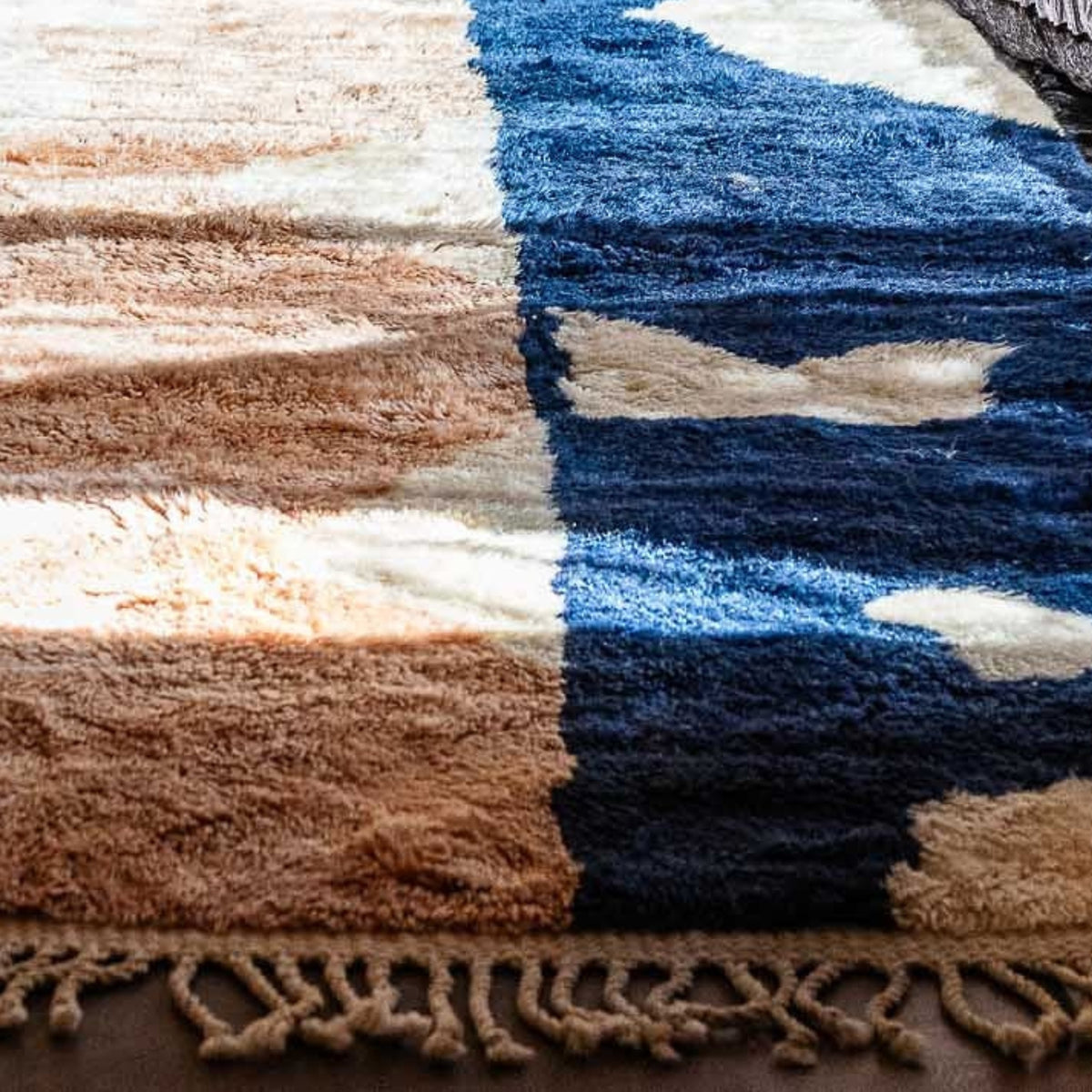 Closeup Handmade Moroccan wool rug blush sand with carved ivory islands and navy stripe