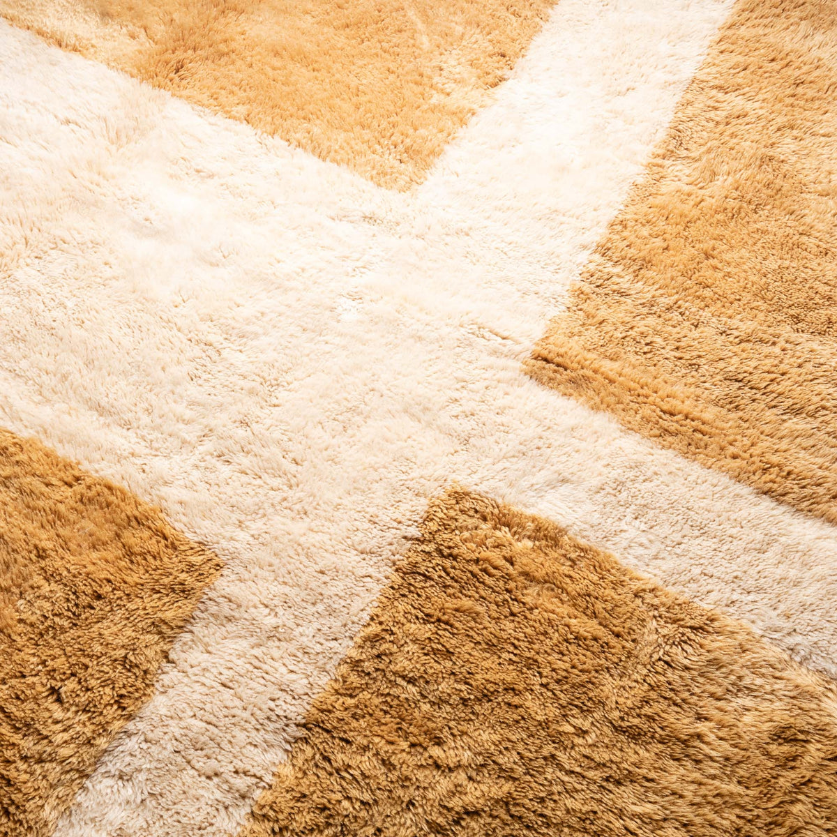 closeup Handmade Moroccan wool rug in golden ochre and cream with bold geometric grid pattern and fringe