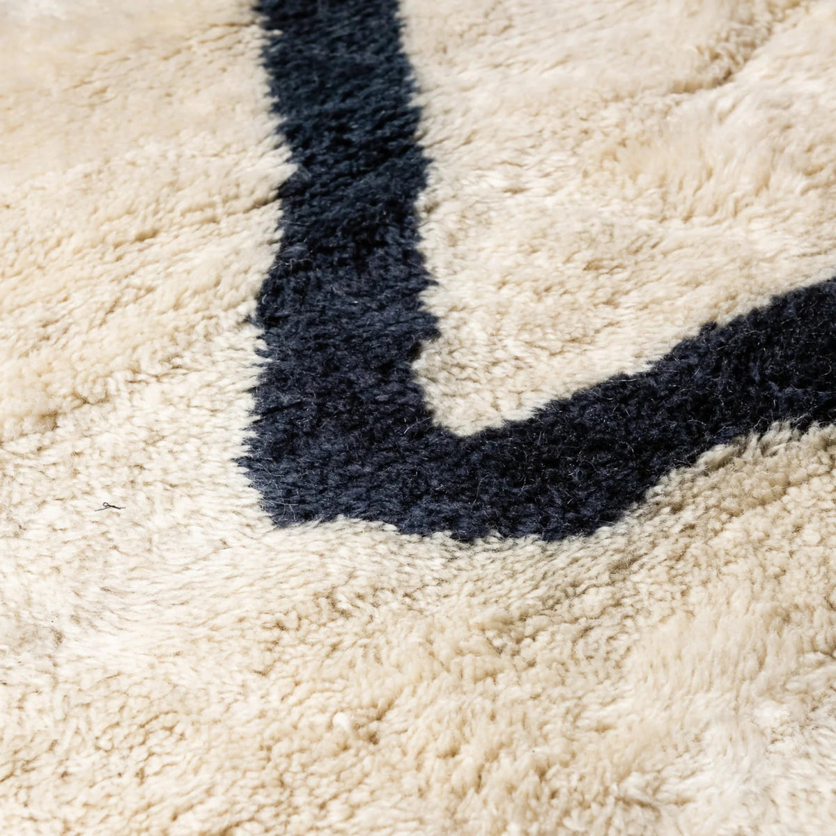 closeup Handmade Moroccan wool rug in ivory with charcoal freeform line motif and fringe