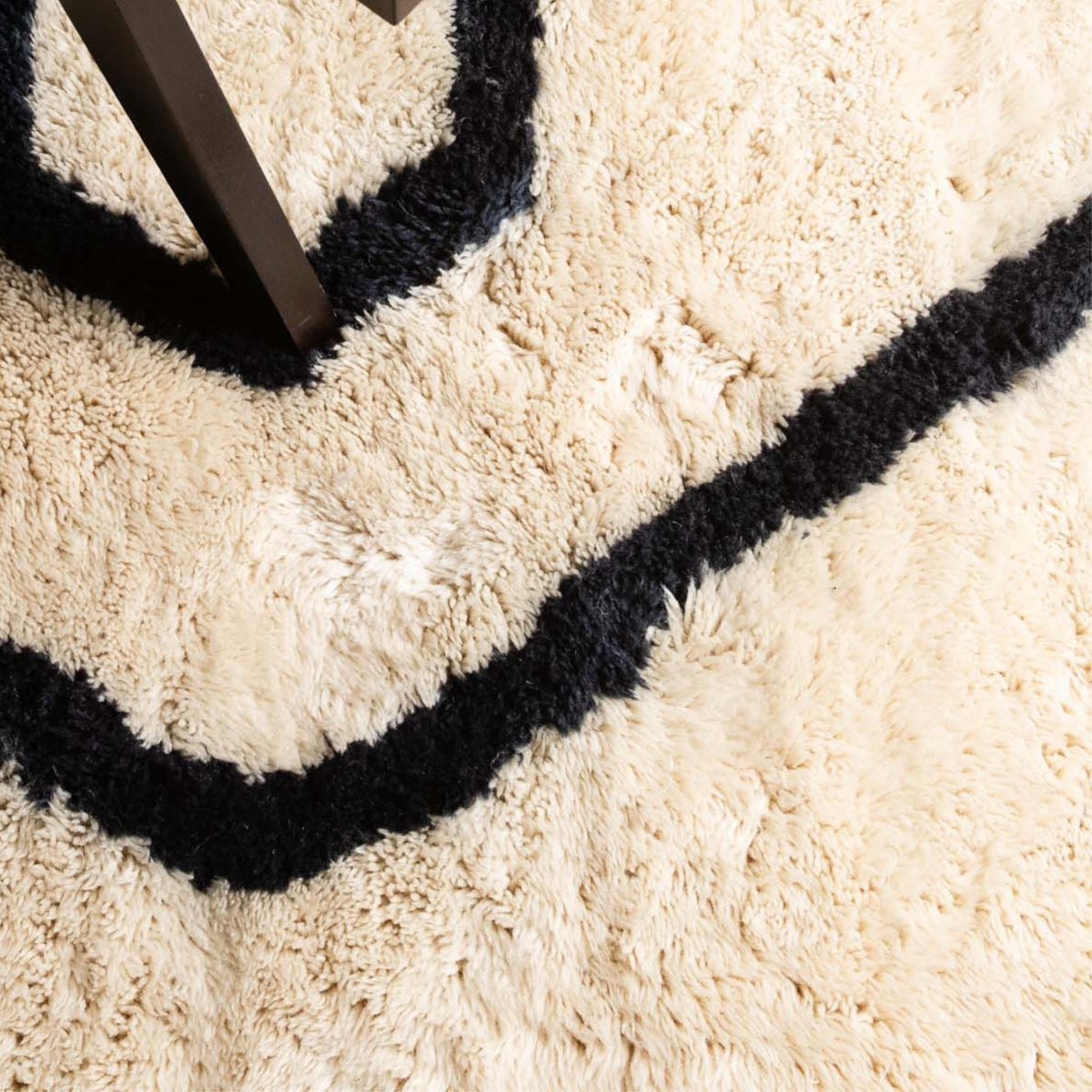 closeup Handmade Moroccan wool rug in ivory with charcoal freeform line motif and fringe