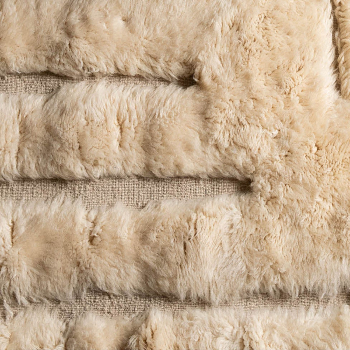 Close up Handmade Moroccan wool rug in ivory cream with carved sand-tone labyrinth relief and fringe