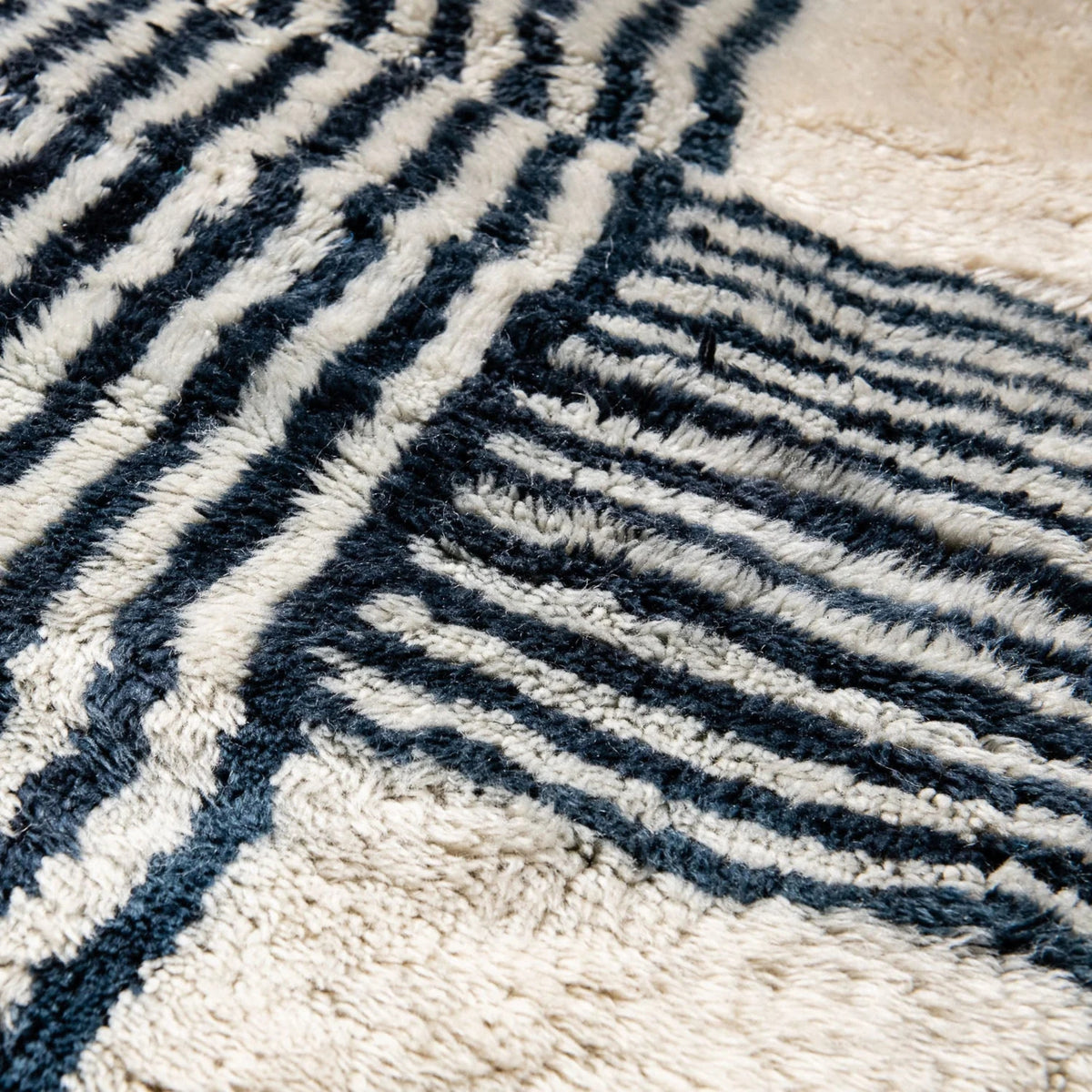 closeup Handmade Moroccan wool rug in cream with navy parallel line chords and fringe