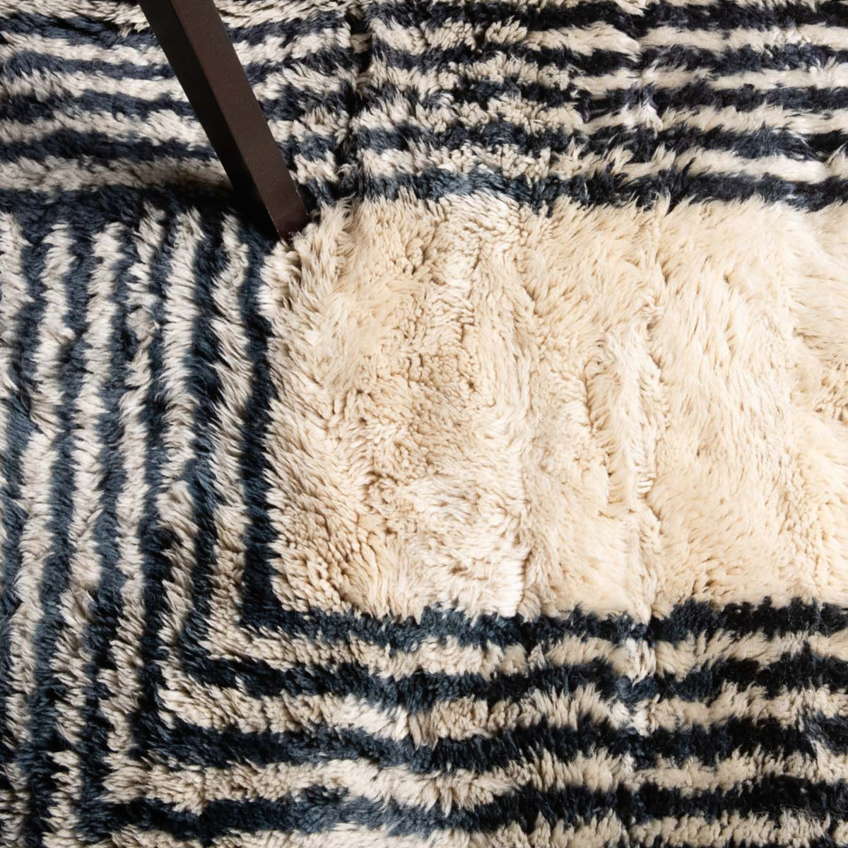 closeup Handmade Moroccan wool rug in cream with navy parallel line chords and fringe