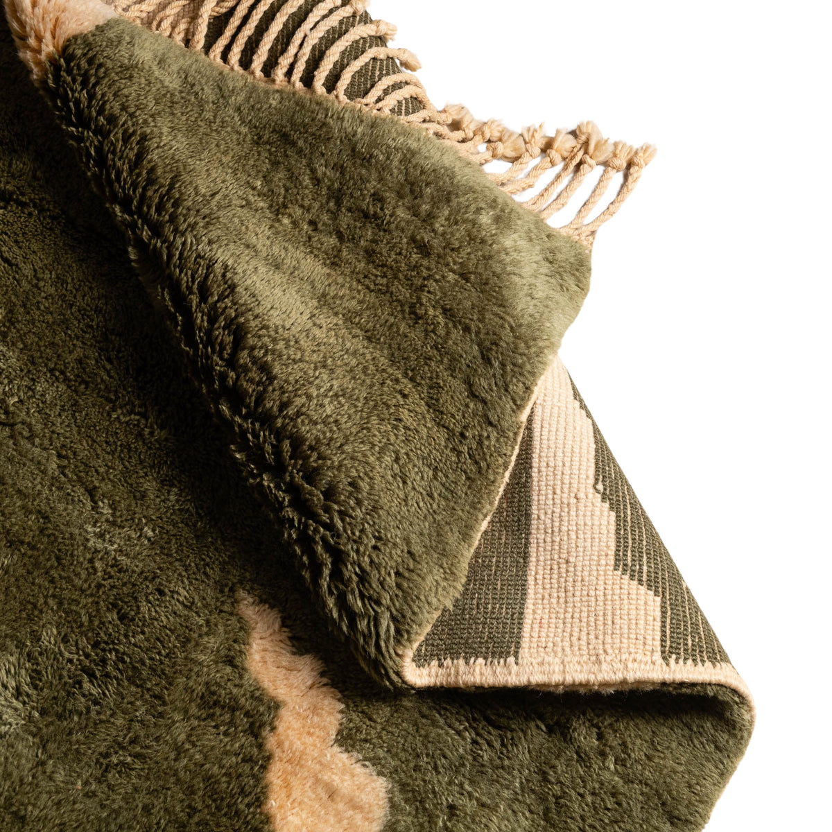 closeup flipped Handmade Moroccan wool rug in olive green and cream with abstract geometric shapes and fringe