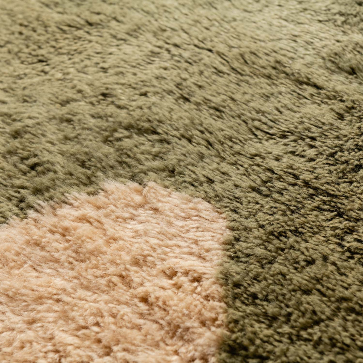 closeup Handmade Moroccan wool rug in olive green and cream with abstract geometric shapes and fringe