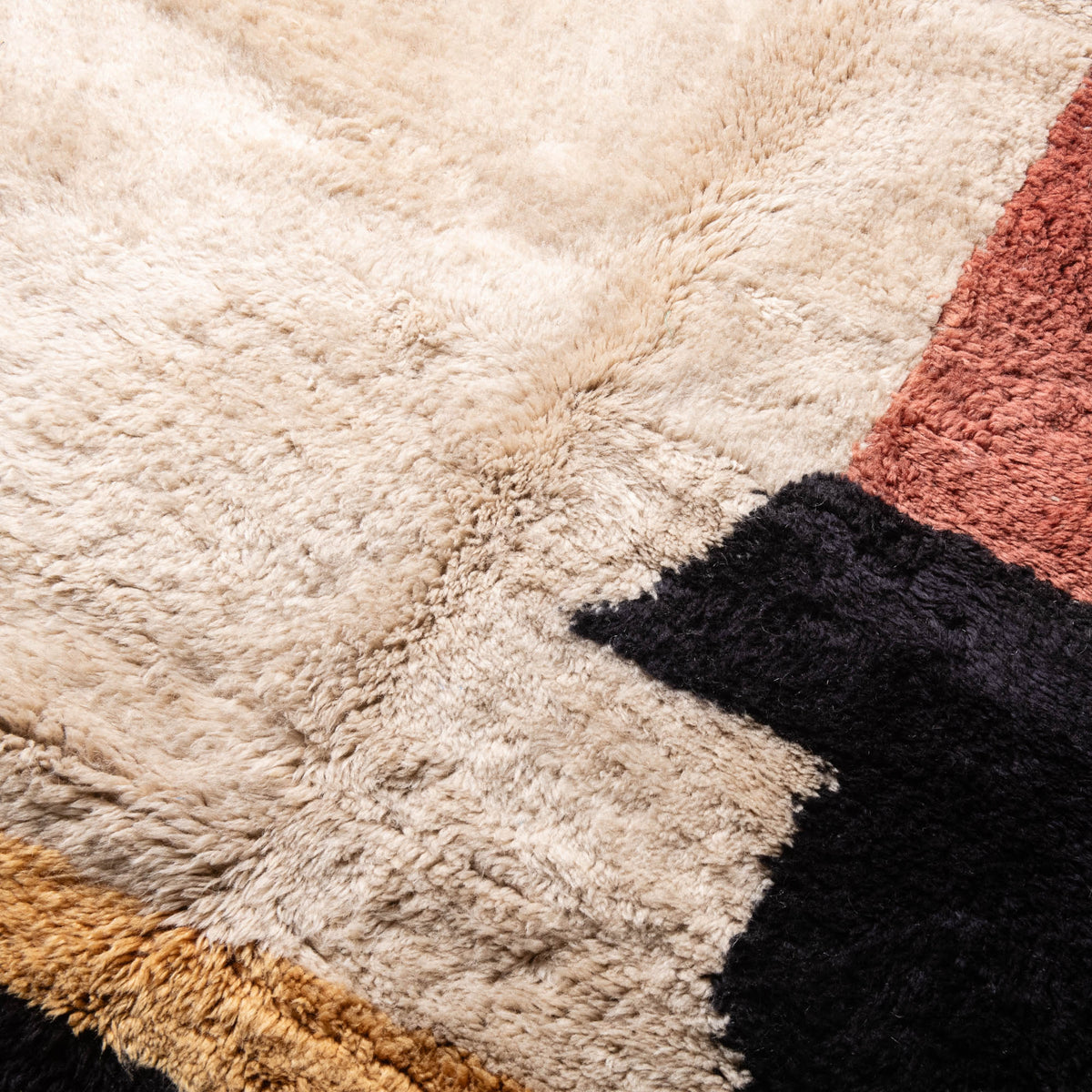 closeup Handmade Moroccan wool rug in cream with rust-red, charcoal, gray, and mustard abstract block design